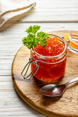 Close-up of red caviar jar with parsley on wooden board
