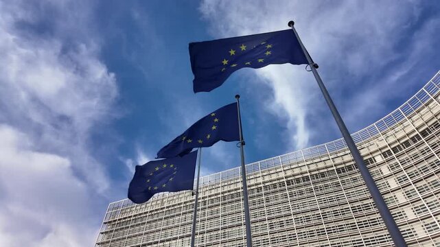 Slow motion European Union flags waving near the Berlaymont building in Brussels.