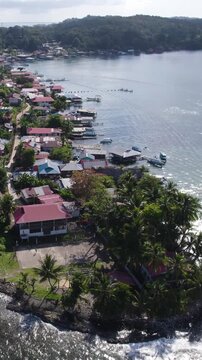 Vertical aerial view of Bastimentos Island in the Bocas del Toro District, showcasing a picturesque coastal village with a circular dolly shot.