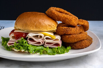 ham and turkey sandwich served with onion rings