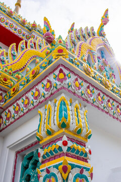 Thai temple with columns and decorative elements with chofahs at the top, a large curved ornament resembling a bird's beak