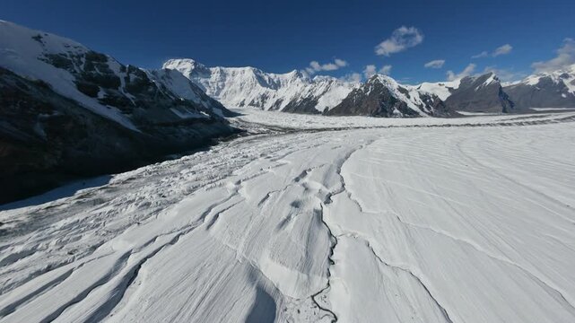 FPV drone flight over the endless South Inylchek glacier. Beautiful snow-capped mountains and cliffs of Kyrgyzstan. Tien Shan. 4K