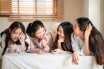 Beautiful asian woman friend happy gossip talking on bed and use smartphone