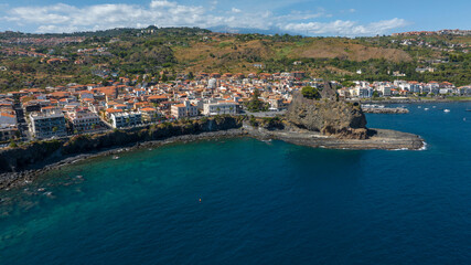 Fototapeta premium Panoramic aerial view of Aci Castello, a coastal village overlooking the Ionian Sea, in the province of Catania, Sicily, Italy. In the foreground is the castle, the town's symbol and attraction.