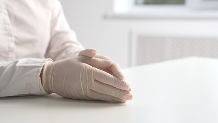 Obraz premium Hands in White Latex Gloves on Table Indoors
