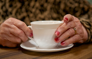 Older woman's hands holding a cup of tea