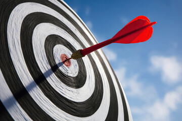 Red dart hitting center of target outdoors