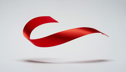 A gracefully floating red satin ribbon creates an elegant abstract curve, symbolizing celebration, awareness, or a special gift against a soft studio background