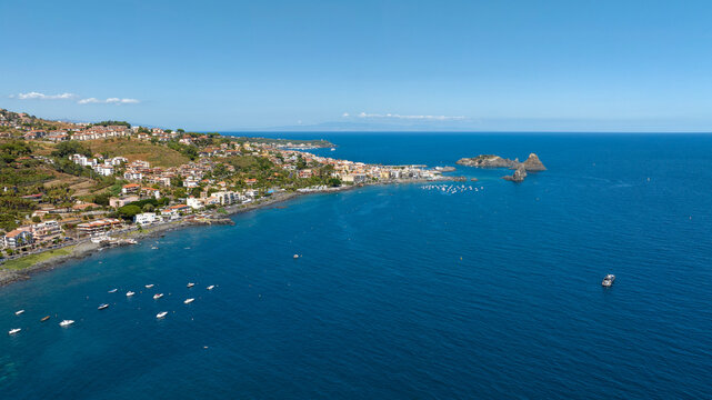 Aerial view of the eastern coast of Sicily overlooking the Mediterranean, Italy. In the background, on the horizon, is the small town of Aci Trezza, in the Province of Catania, Sicily.