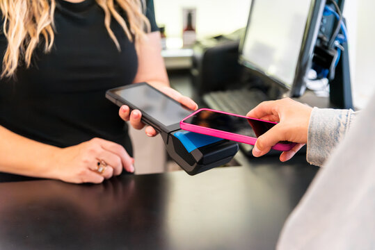 Customer making contactless payment using smartphone at checkout - Powered by Adobe