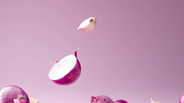 Fresh red onions and garlic cloves floating against a soft pink background