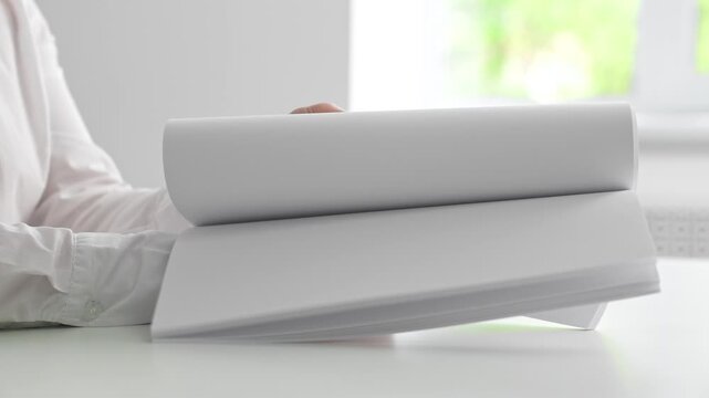 Person in White Shirt Holding a Thick Stack of Papers