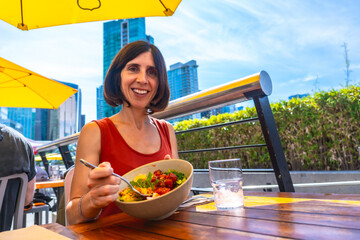 Fototapeta premium Woman eating healthy poke bowl in vancouver restaurant patio