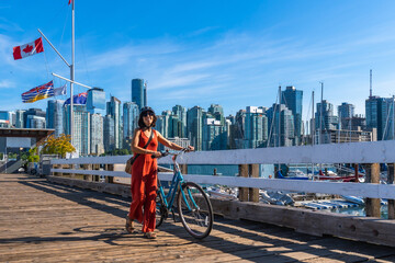 Obraz premium Tourist walking with bicycle on pier, enjoying vancouver skyline