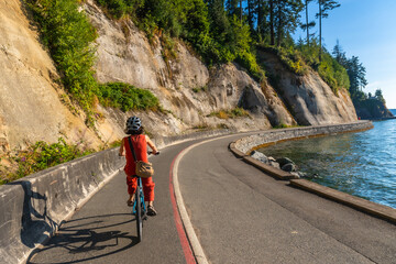 Tourist riding bicycle in stanley park seawall, vancouver, british columbia