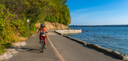 Obraz premium Woman cycling along stanley park seawall in vancouver, british columbia