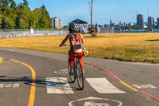 Woman cycling in kitsilano beach park with vancouver skyline in background