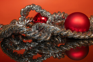 Rote Christbaumkugel mit silberner Kordel auf einer schwarzen Acrylplatte