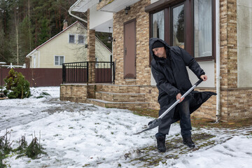 Elderly man shoveling snow in winter yard 
