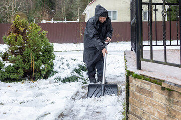 Elderly man shoveling snow in winter yard