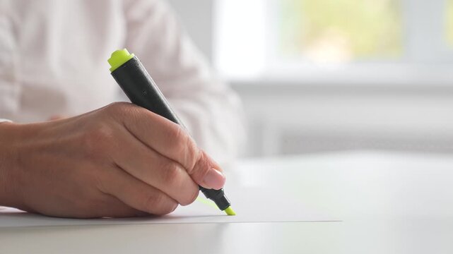 Hand Holding Highlighter Marking Paper in Office