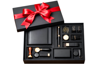 Luxury black gift box with red ribbon containing elegant accessories, wax seal, notebook and premium stationery items arranged in compartments creating refined masculine gift presentation