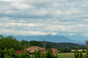 Rural scene in the medieval village Peratallada in Baix Emporda region of Girona plain of Catalonia, Spain, with the snow-capped Pyrenees mountains in the background and traditional farmhouse or masia