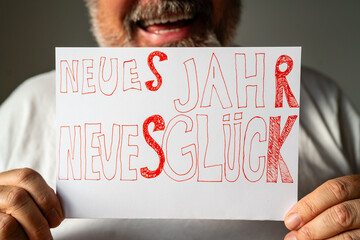 Lachender b&auml;rtiger Mann h&auml;lt Schild mit handgeschriebenem Spruch Neues Jahr Neues Gl&uuml;ck. Positive Neujahrsw&uuml;nsche und Optimismus