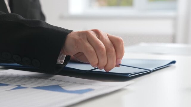 Businessperson Hand on Blue Document Folder in Office