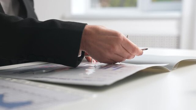 Hands holding a spring loaded folder with documents on an office desk.