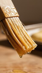 Close Up Of A Wooden Pastry Brush Dripping With Golden Syrup On A Wooden Surface With Natural Light