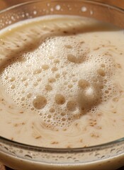 Close up of Active Dry Yeast Bubbling in Warm Water Creating Frothy Foam Texture in Glass Bowl Warm and Inviting Culinary Preparation Scene