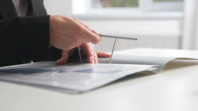 Hands holding a spring loaded folder with documents on an office desk.