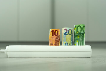 rolled euro banknotes in power strip illustrating high electricity prices in the european union and the rising cost of household energy during the utility crisis
