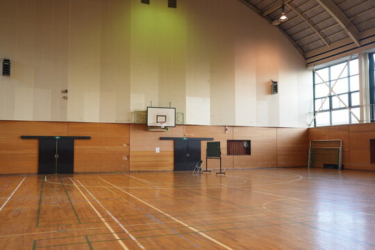 A gymnasium with a basketball court and a bench. The court is empty and the bench is in the middle of the court