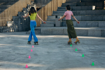 Girl friends weave around colored markers keeping stable posture

