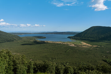 Italy - Lazio - Lago di Vico - Elevated panoramic view volcanic crater lake forested hills green landscape blue water sky and clouds