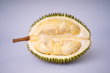 Obraz premium Premium shot of a halved durian fruit, revealing rich creamy yellow pulp and a sharp spiky husk. Fresh tropical exotic fruit isolated on a plain white background
