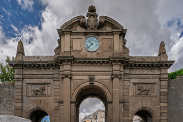 Italy - Viterbo - Porta Fiorentina - Neoclassical north gate with clock and lion reliefs on medieval walls under summer clouds sky © Guillaume