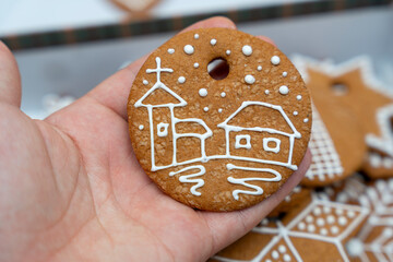 Handheld view of a gingerbread cookie featuring a decorated house and church design. Ideal for festive holiday themes and culinary promotion. Perfect for baking and Christmas decorations.