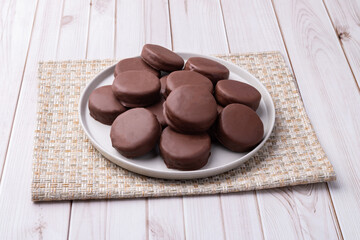 Brazilian Pao de Mel or chocolate covered honey cookies over a wooden table