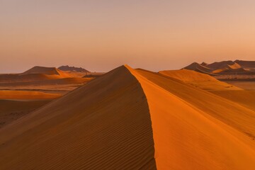 Dramatic Sunset Over Rolling Sand Dunes in Desert Landscape