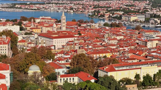 Aerial drone view over Zadar's historic Old Town showcasing a dense pattern of terracotta rooftops, Romanesque churches, medieval towers, and narrow streets