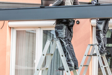 Workers install patio roofing with steel and glass