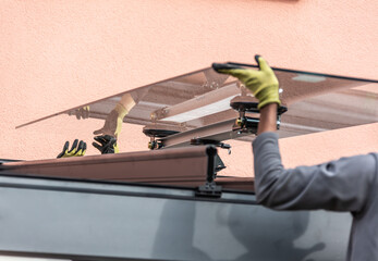 Workers install patio roofing with steel and glass