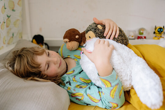 Child enjoys bedtime with stuffed animals and smiles in cozy room setting