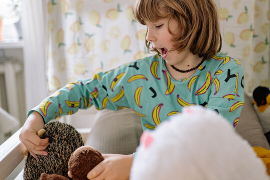 Child plays with stuffed animals in a cozy room during the afternoon