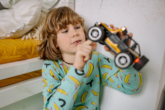Boy plays with toy car in bedroom while wearing pajamas in the evening