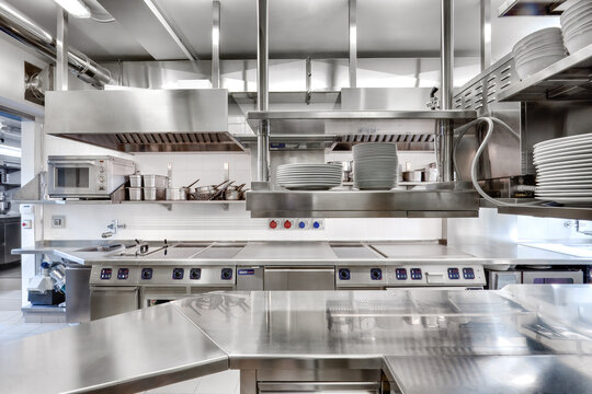 Modern industrial kitchen with digital stovetops, stainless appliances, cookware racks, and organized prep zones&mdash;ideal for high-efficiency cooking.