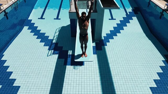 Man standing on diving board at outdoor swimming pool with blue tiles 4k video